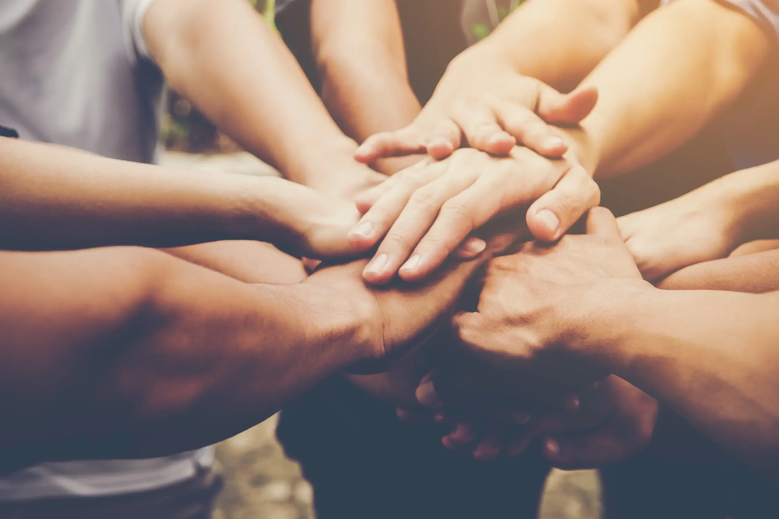 Des mains unies en cercle, symbole de solidarité et de collaboration, lors d’un atelier de formations pour entreprises axé sur la cohésion d’équipe. Une image puissante pour représenter l’esprit d’équipe et la confiance mutuelle au travail.